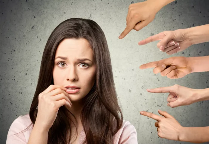 Toung woman blushing with accusatory hands pointing at her
