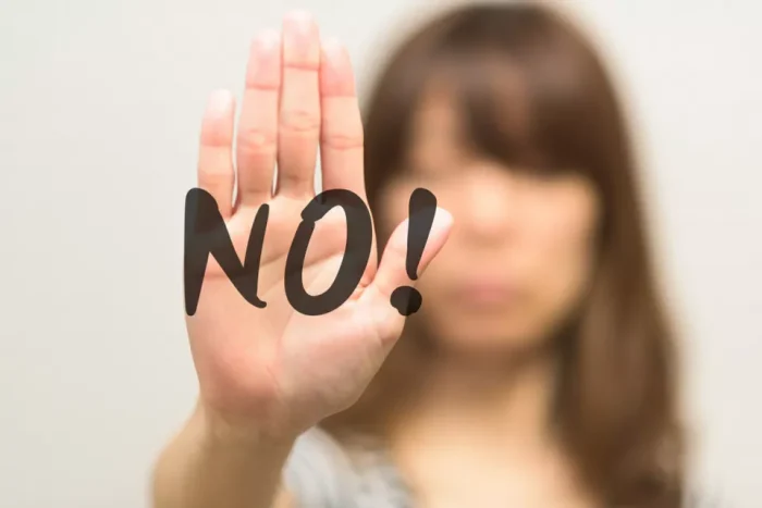 Woman holding up her hand with the word 'NO'