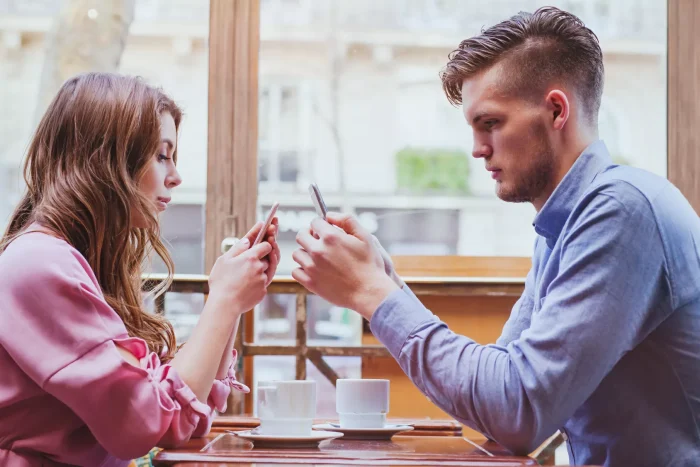 Couple sitting opposite each other using their smart phones