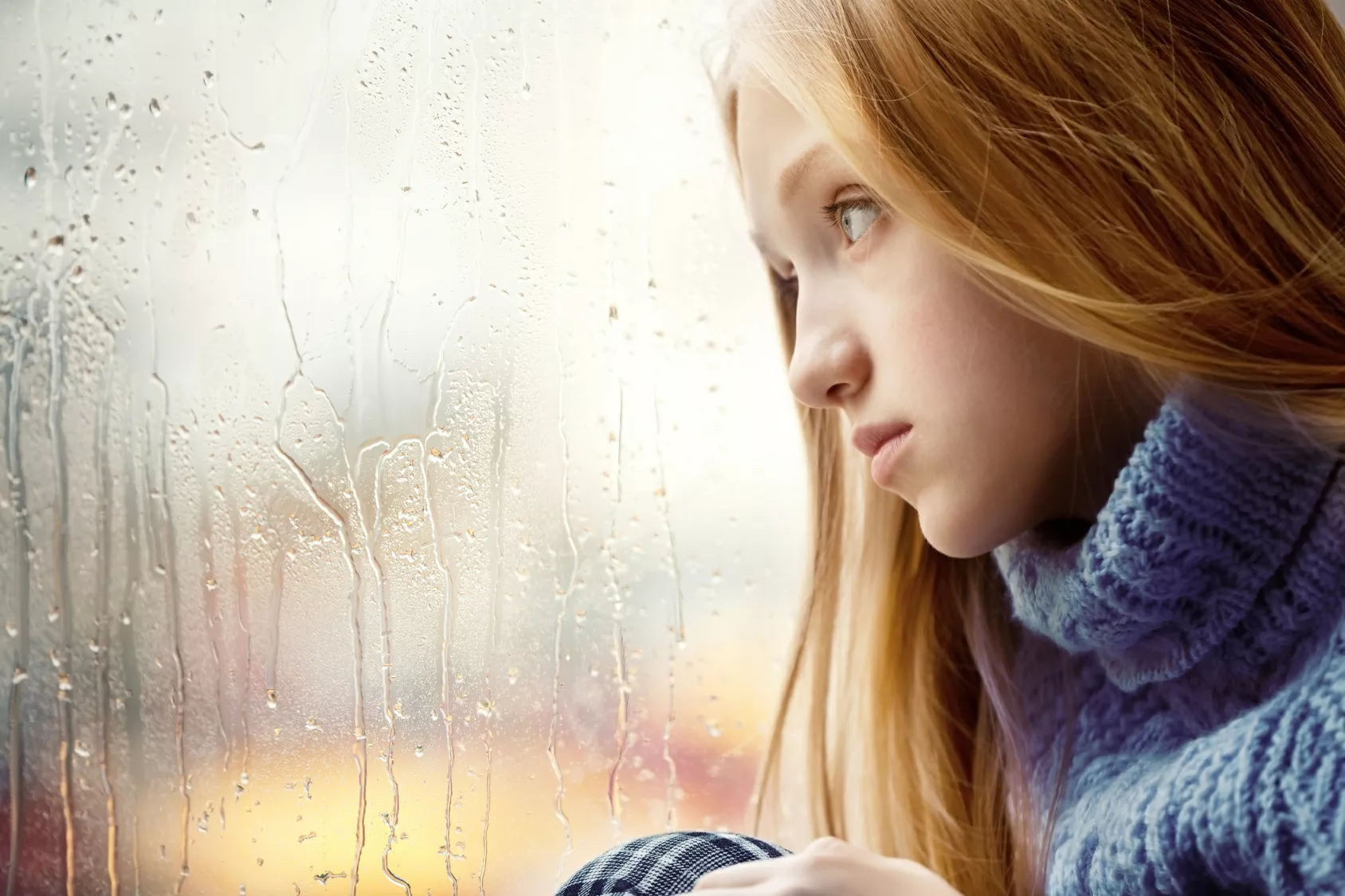 depressed woman gazing out of rain-soaked window