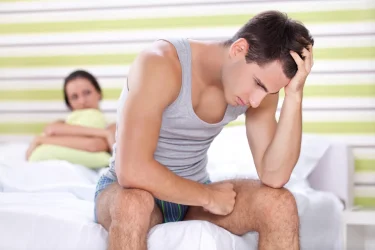 Man with PE sitting on side of bed with female partner
