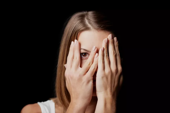 Woman hiding her face with her hands, afraid of being seen