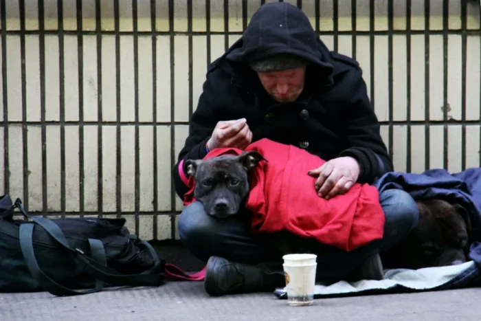 Homelesws man with his dog and sleeping bag on the street