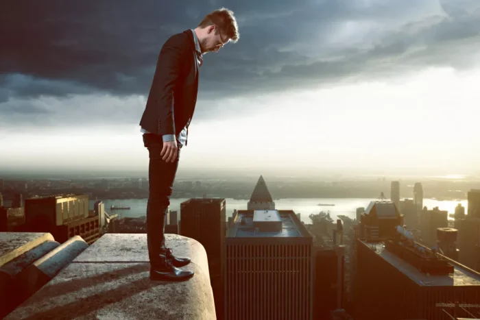 Man standing on the edge of a tall skyscraper looking down