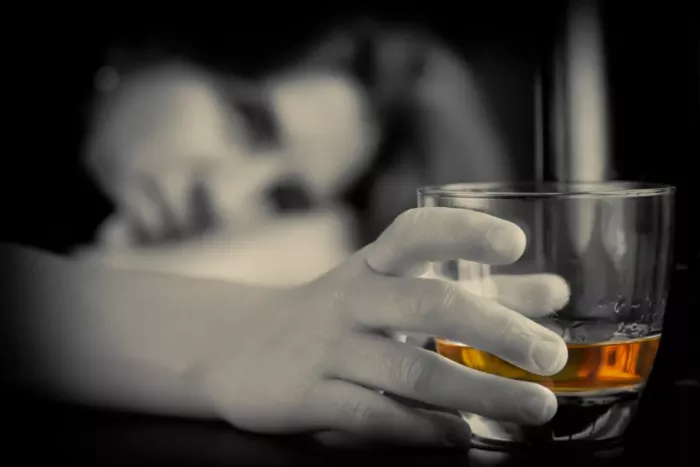 female with alcohol addiction gazing at glass of whiskey