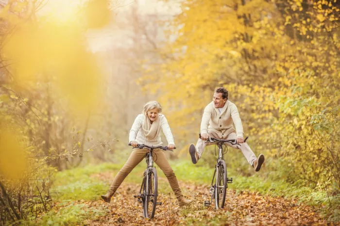 Middle-aged couple riding bikes in a autumn wood